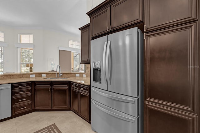 kitchen with light stone countertops, sink, light tile patterned floors, and stainless steel appliances