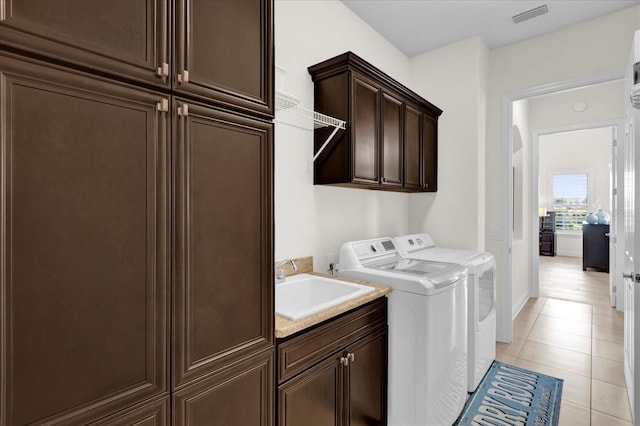 laundry room with washer and clothes dryer, sink, light tile patterned flooring, and cabinets