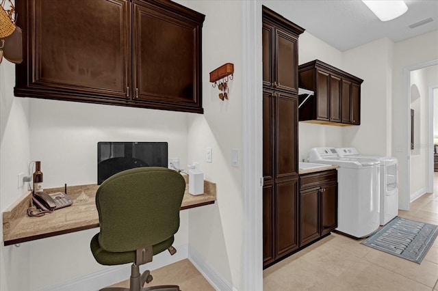 laundry area featuring separate washer and dryer, light tile patterned floors, and cabinets