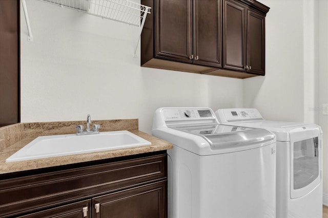 clothes washing area with cabinets, washer and clothes dryer, and sink