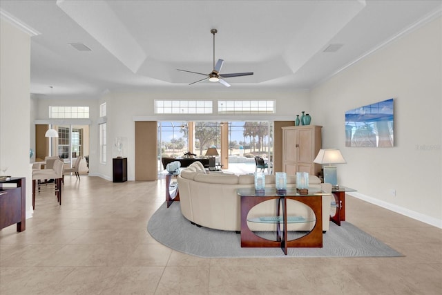 tiled living room with ceiling fan, ornamental molding, and a tray ceiling