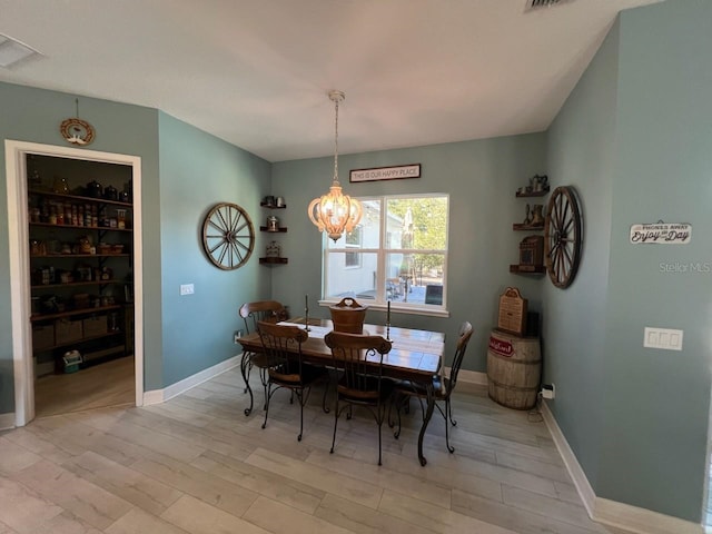 dining room with light hardwood / wood-style flooring and an inviting chandelier