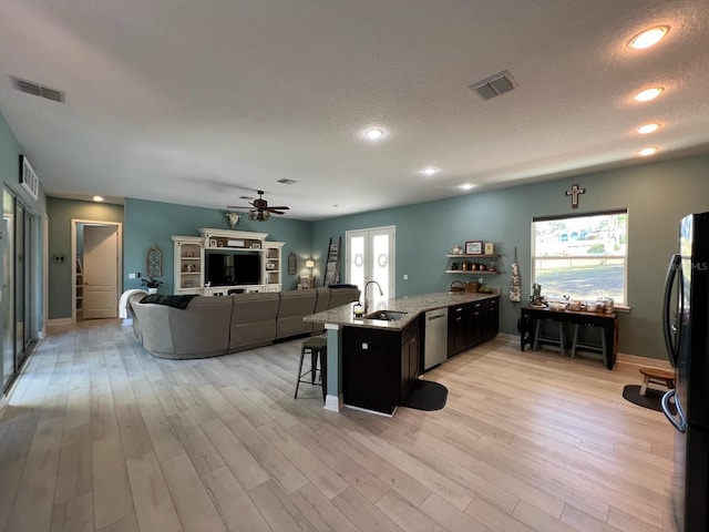 kitchen with a kitchen breakfast bar, sink, stainless steel dishwasher, ceiling fan, and fridge