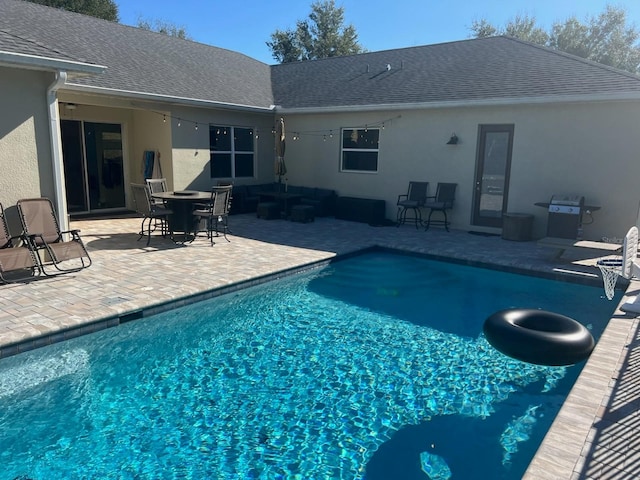 view of pool with outdoor lounge area, a grill, and a patio area