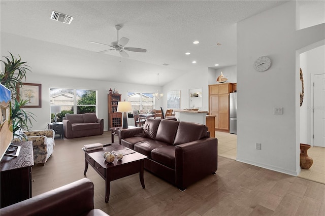 living room with a textured ceiling, ceiling fan with notable chandelier, light hardwood / wood-style floors, and lofted ceiling