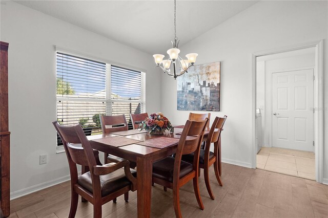 dining space featuring a notable chandelier, light wood-type flooring, and lofted ceiling