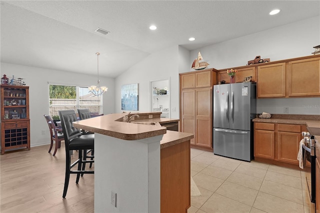 kitchen featuring sink, stainless steel appliances, a chandelier, pendant lighting, and a kitchen bar