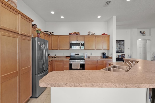 kitchen featuring sink, light tile patterned flooring, stainless steel appliances, and a center island with sink