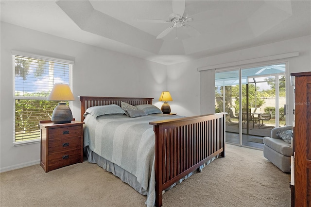 bedroom featuring a raised ceiling, access to exterior, ceiling fan, and multiple windows