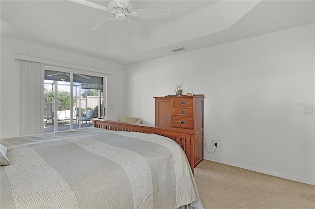 carpeted bedroom with access to exterior, a raised ceiling, and ceiling fan