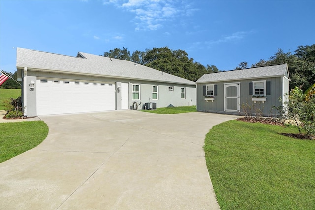 single story home featuring an outbuilding, central AC unit, a front yard, and a garage