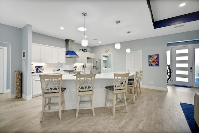 kitchen featuring stainless steel fridge, white cabinetry, a spacious island, and decorative light fixtures