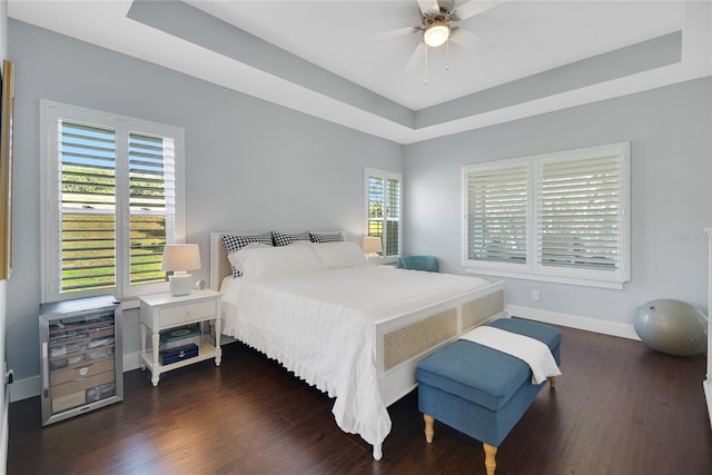 bedroom with a tray ceiling, ceiling fan, and dark hardwood / wood-style floors