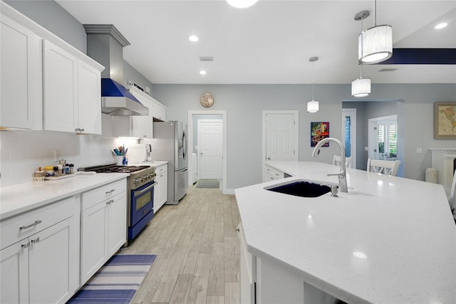 kitchen with white cabinets, hanging light fixtures, stainless steel appliances, and a large island with sink