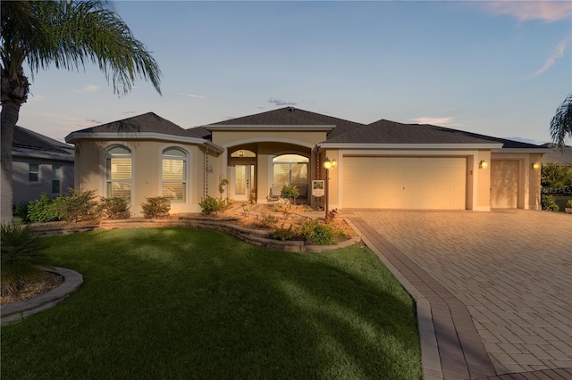 view of front of property with a garage and a lawn