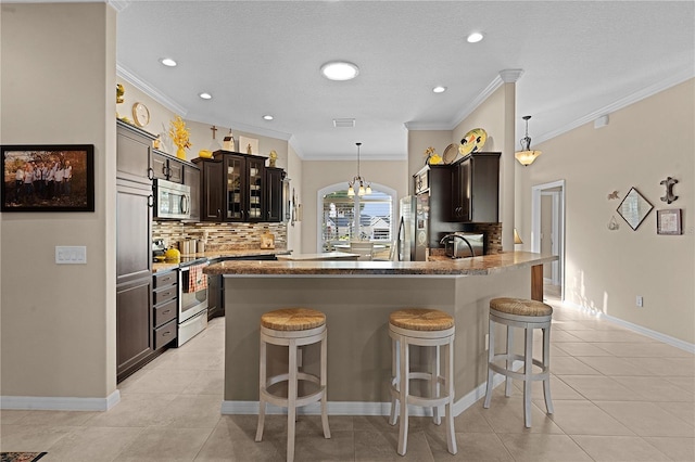 kitchen featuring kitchen peninsula, tasteful backsplash, dark brown cabinets, stainless steel appliances, and crown molding