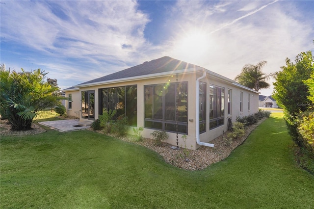 rear view of house featuring a sunroom, a patio area, and a lawn