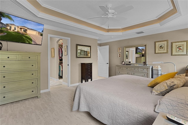 bedroom featuring a raised ceiling, ceiling fan, a spacious closet, and ornamental molding