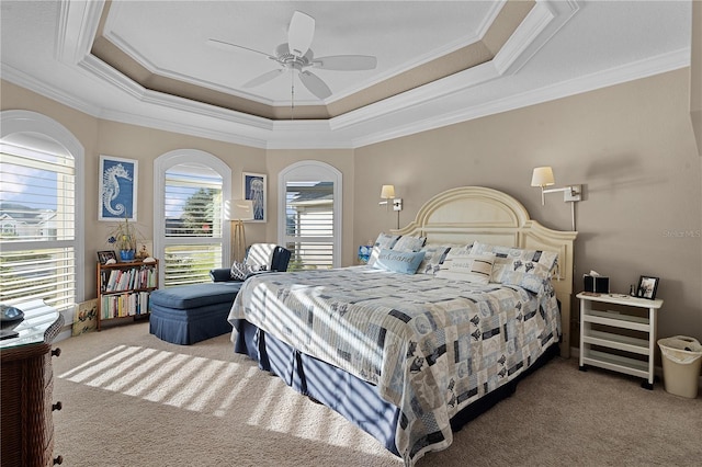 carpeted bedroom featuring ceiling fan, a raised ceiling, and ornamental molding