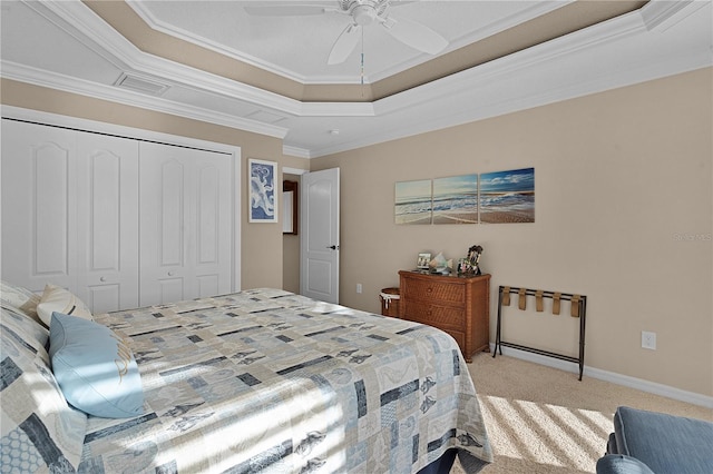 carpeted bedroom featuring ceiling fan, a closet, crown molding, and a tray ceiling