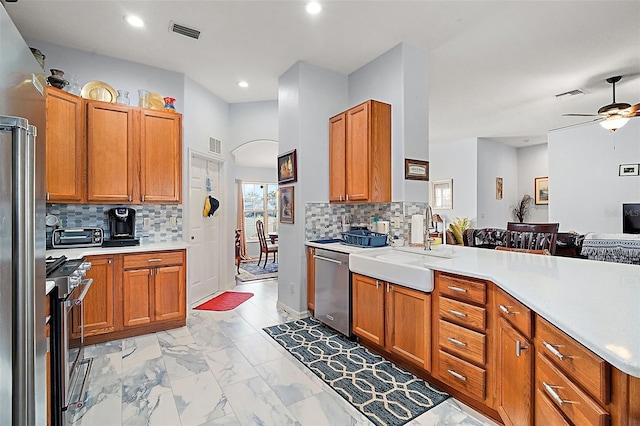 kitchen with kitchen peninsula, appliances with stainless steel finishes, decorative backsplash, ceiling fan, and sink