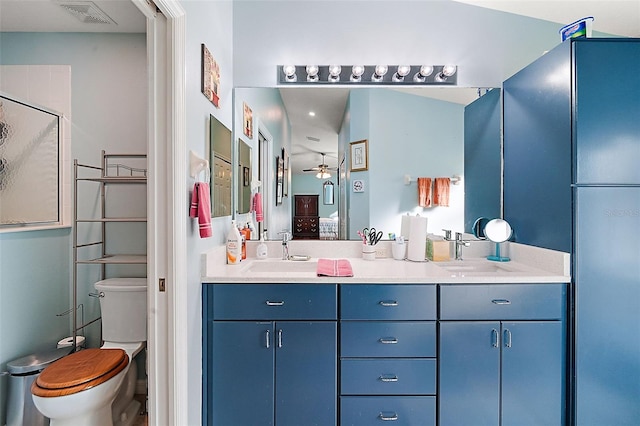 bathroom featuring ceiling fan, a shower with door, vanity, and toilet