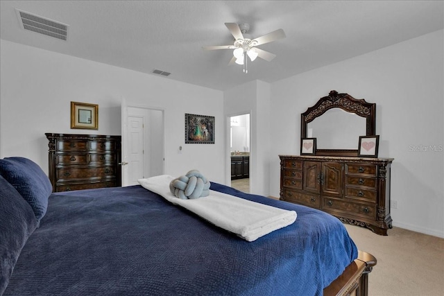 bedroom featuring light colored carpet, ensuite bath, and ceiling fan