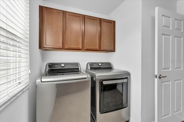 laundry room with washer and clothes dryer, a healthy amount of sunlight, and cabinets