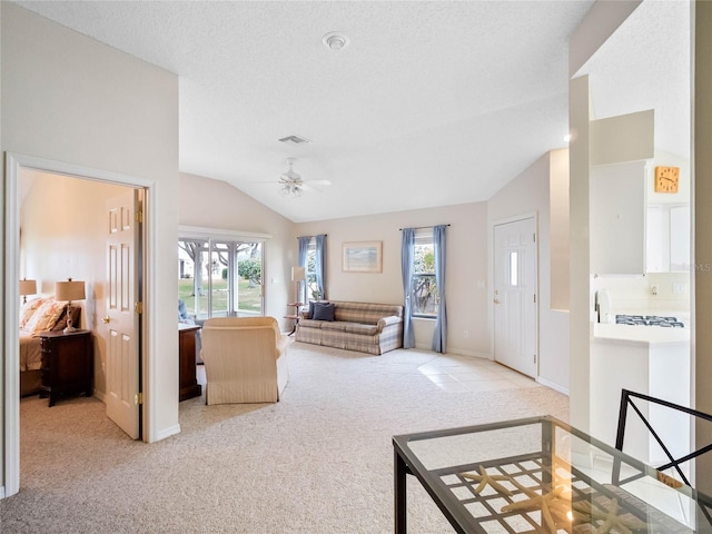 living room featuring light carpet, a textured ceiling, vaulted ceiling, and ceiling fan