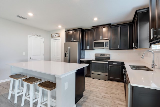 kitchen with a center island, sink, stainless steel appliances, tasteful backsplash, and a breakfast bar