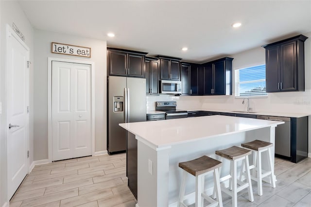 kitchen featuring sink, a breakfast bar area, decorative backsplash, a kitchen island, and stainless steel appliances