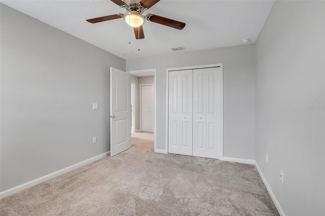 unfurnished bedroom with ceiling fan, light carpet, and a closet