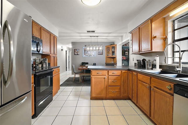 kitchen featuring pendant lighting, black appliances, sink, light tile patterned floors, and kitchen peninsula