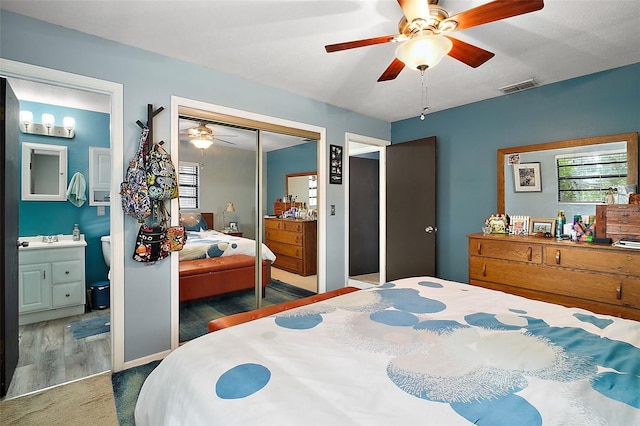 bedroom featuring dark colored carpet, connected bathroom, a closet, and ceiling fan