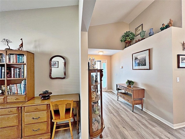 interior space featuring light wood-type flooring, high vaulted ceiling, and built in desk