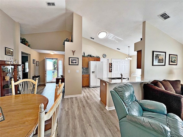 interior space featuring sink, a chandelier, vaulted ceiling, and light wood-type flooring