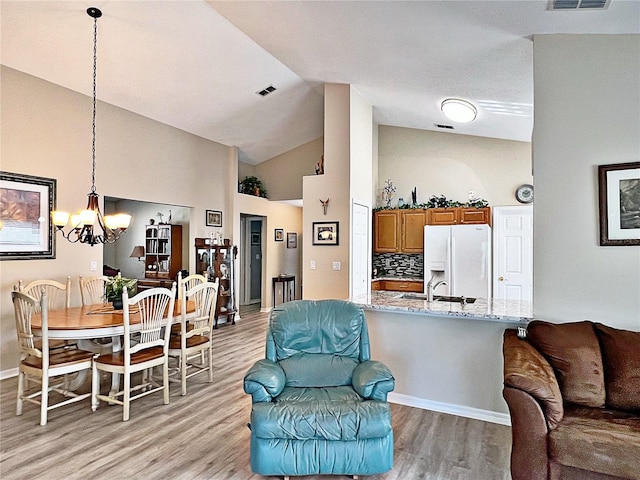 living room with light hardwood / wood-style floors, high vaulted ceiling, and an inviting chandelier