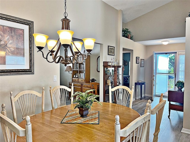 dining area with an inviting chandelier, wood-type flooring, and vaulted ceiling