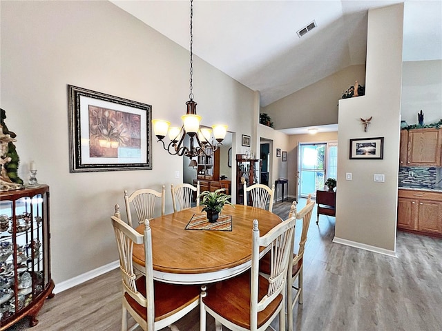 dining space with light wood-type flooring, lofted ceiling, and a notable chandelier