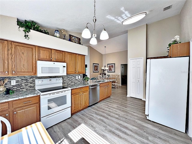 kitchen with hanging light fixtures, an inviting chandelier, high vaulted ceiling, backsplash, and white appliances