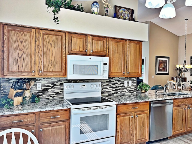 kitchen with tasteful backsplash, light stone counters, white appliances, sink, and pendant lighting