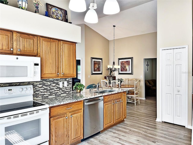 kitchen featuring pendant lighting, white appliances, high vaulted ceiling, sink, and light stone counters