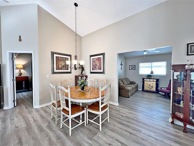 dining room with ceiling fan, high vaulted ceiling, and hardwood / wood-style flooring