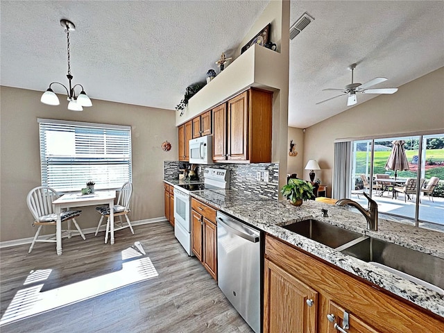 kitchen featuring backsplash, ceiling fan with notable chandelier, white appliances, vaulted ceiling, and pendant lighting