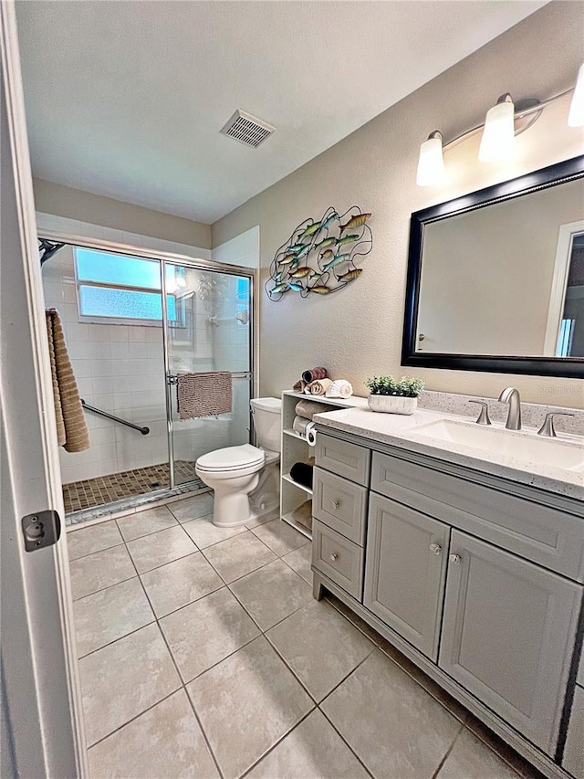 bathroom with tile patterned flooring, vanity, toilet, and a shower with door