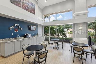 dining area with a towering ceiling, light hardwood / wood-style floors, plenty of natural light, and sink