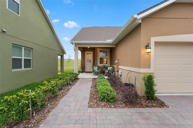 view of exterior entry featuring a porch and a garage