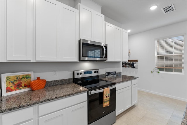 kitchen featuring stainless steel appliances, dark stone countertops, and white cabinets