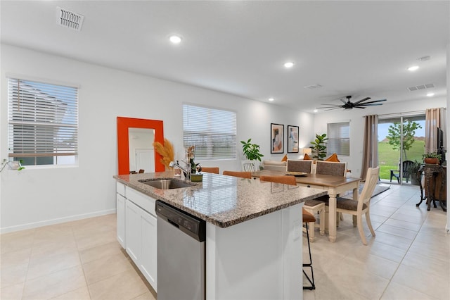 kitchen featuring sink, light stone countertops, an island with sink, white cabinets, and stainless steel dishwasher