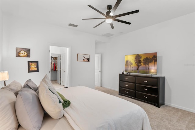 carpeted bedroom with a walk in closet, a closet, and ceiling fan